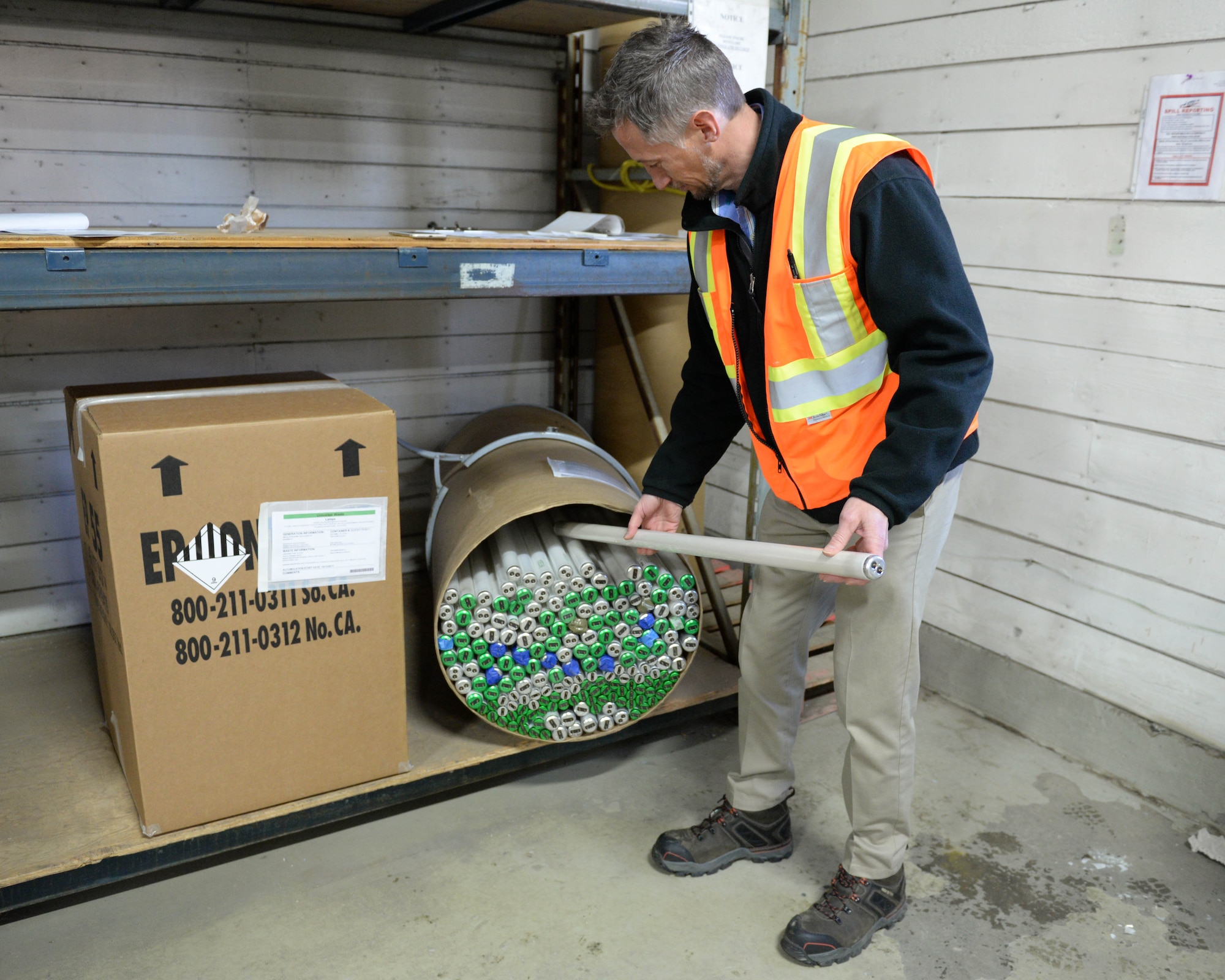 Scott Tarbox, JBER hazardous waste manager, demonstrates the proper placement of a fluorescent lamp in a properly labeled and sealable container at Joint Base Elmendorf-Richardson, Alaska, Nov. 8, 2017. Fluorescent lamp bulbs are considered universal waste, so the proper storage, labeling and disposal of them are regulated by Title 40 of the Code of Federal Regulation Part 273.