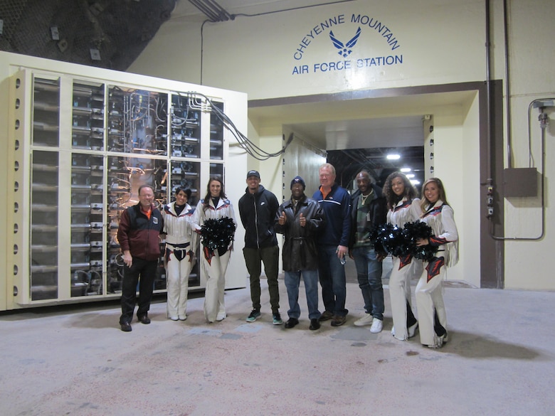 Current and Former Denver Broncos player, Cheerleaders and staff, stand in front of the blast doors with Steve Rose, 721st Mission Support Group deputy director, at Cheyenne Mountain Airforce Station, Colorado, on Nov. 8, 2017. Denver Broncos personnel toured Cheyenne Mountain to learn about the 21st Space Wing’s mission, vision and goals. (U.S. Air Force photo by Staff Sgt. Erica Picariello)