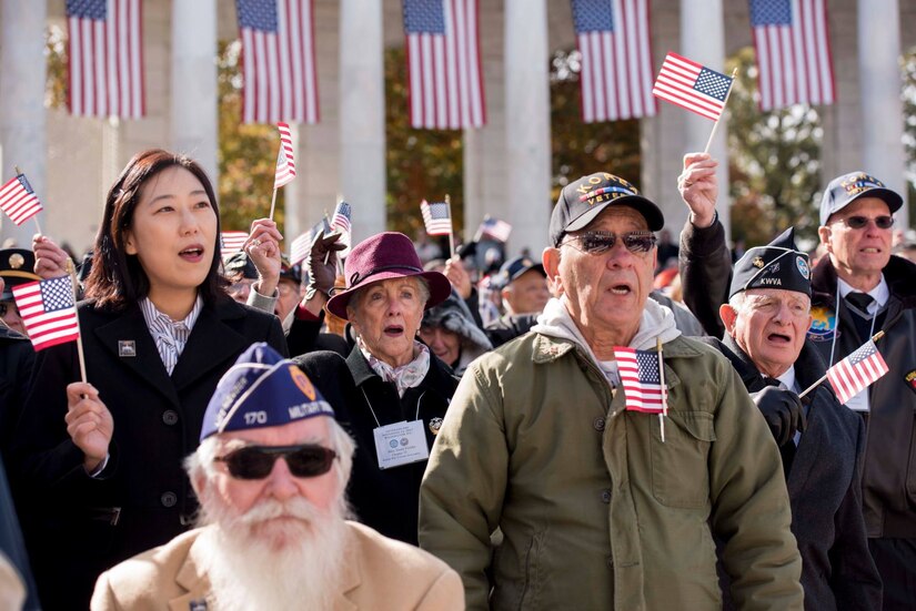 Participants of Veterans Day ceremony wave American flags