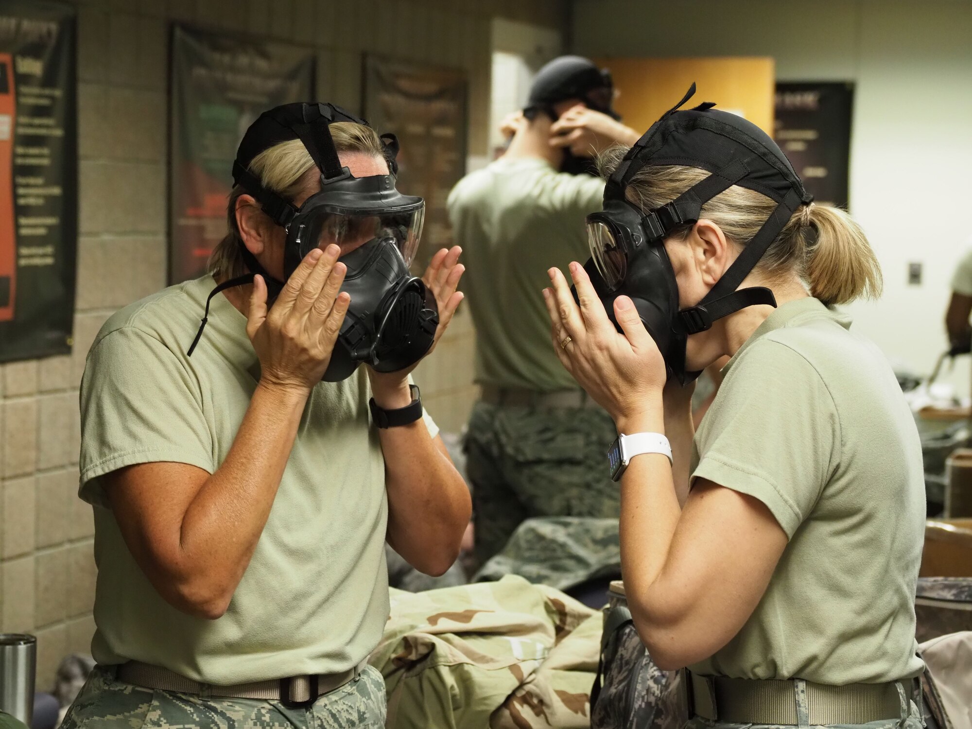 Master Sgt. Jody Knight (left) and Lt. Col. Erika Cashin test their gas mask fit during an Ability to Survive and Operate exercise Nov. 4. (Air Force photo/Paul Zadach)