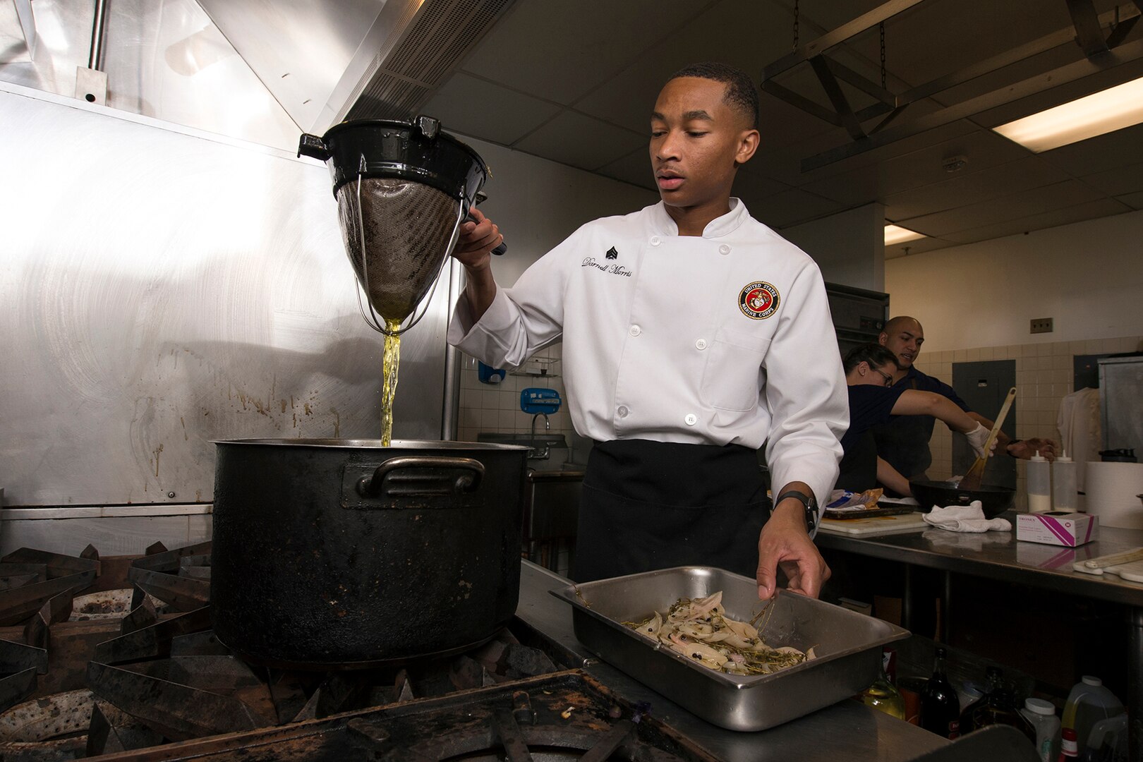 A military chef strains a liquid