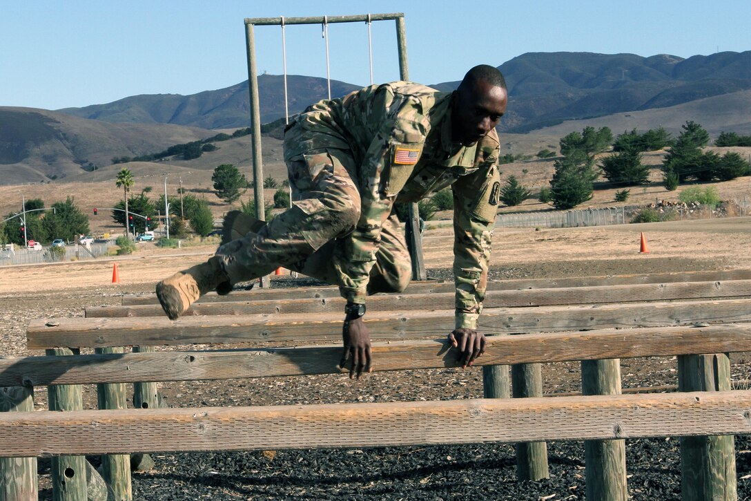 Army Spc. Deng A. Deng leaps over the high hurdle obstacle.