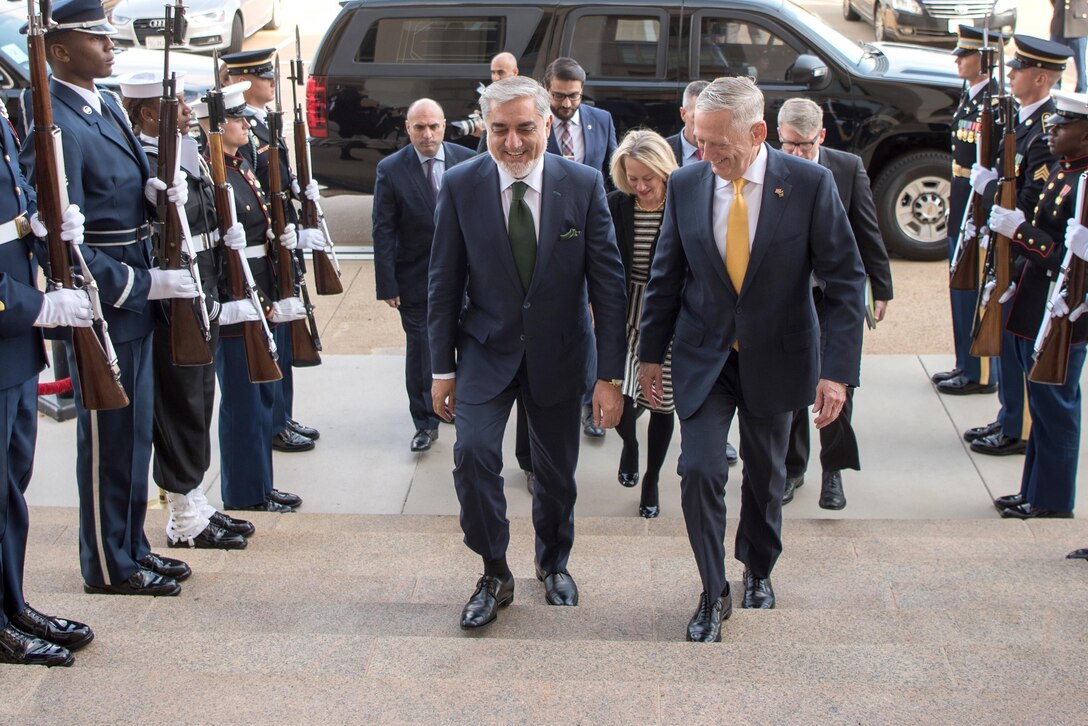 Defense Secretary Jim Mattis walks up steps with another person.