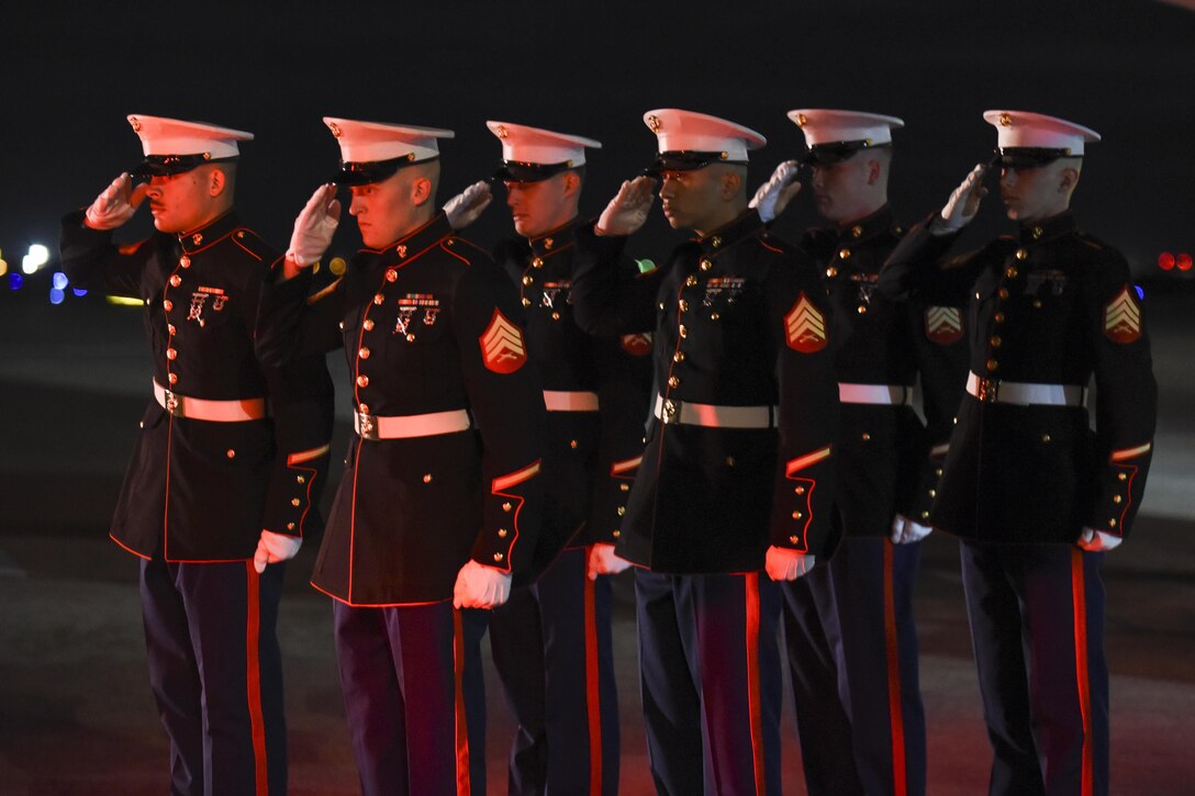 Red light bathes the faces of Marines from Rocket Battery F, 2nd Battalion, 14th Marine Regiment, 4th Marine Division as they salute the hearst carrying the remains of Marine Corps Pvt. Vernon Paul Keaton November 14, 2017, Will Rogers World Airport, Oklahoma City, Oklahoma.