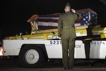 Gunnery Sgt. Nicholas Brundige, Assistant Marine Corps funeral director, Marine Headquarters Barracks, Washington, D.C., salutes the flag draged casket containing the remains of Marine Corps Pvt. Vernon Paul Keaton, as it moves down the conveyor belt after arriving at Will Rogers World Airport November 14, 2017, Oklahoma City, Oklahoma.
