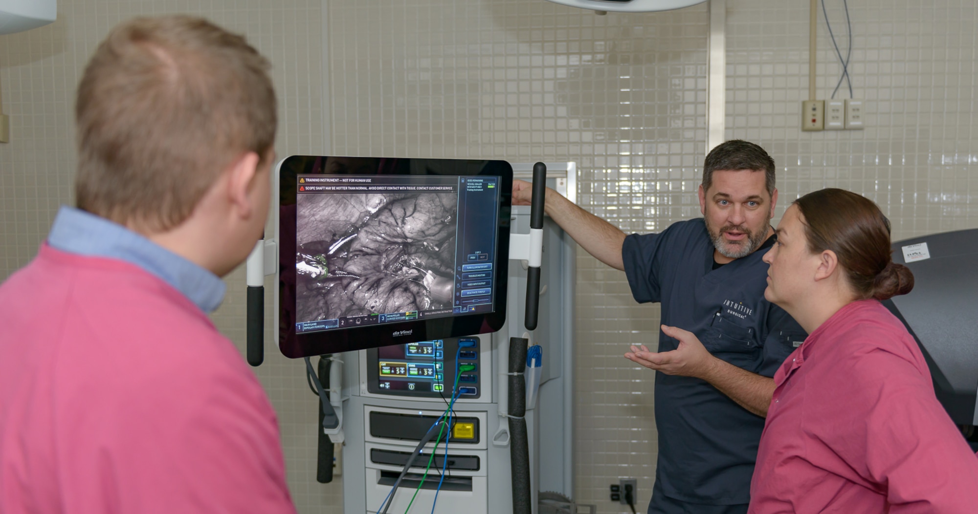 Jon Martin, Intuitive Surgical customer trainer, (center), discusses the DiVinci Xi surgical system at the Clinical Research Lab with Dr. Svyatoslav Guznor, 711th Human Performance Wing Airman systems directorate research psychologist, and Capt. Breanna Raney, 711th HPW Airman systems directorate program manager, Air Force Research Lab, Wright-Patterson Air Force Base, Ohio, Nov. 14, 2017, on Keesler Air Force Base, Mississippi. Guznor and Raney visited Keesler to get a better understanding of robotics surgery in the Air Force by touring the InDorse Lab and observing surgeons, nurses, and techs to get basic training on the Da Vinci machine. They also interviewed surgical staff and system trainers on their interactions with the robot and the team dynamics, and collaborated with the lead robotic surgeon about future joint ventures and research collaborations. (U.S. Air Force photo by Andre’ Askew)