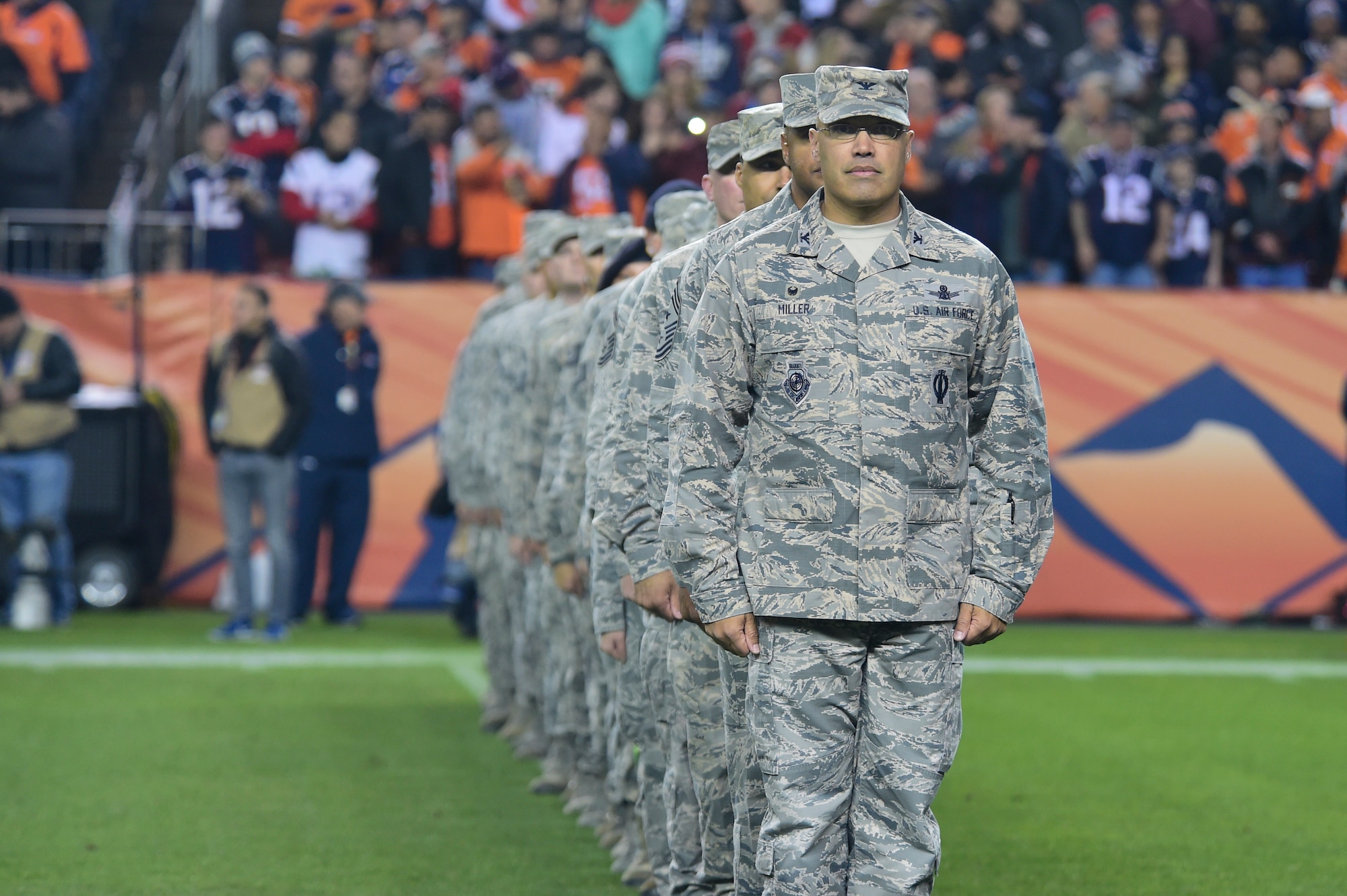 Col. David Miller, Jr., 460th Space Wing commander, leads Buckley Air Force Base members onto the 40-yard line as they prepare for the Salute to Service pre-game ceremony to begin Nov. 12, 2017, at Sports Authority Stadium at Mile High in Denver.