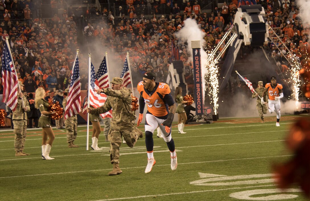 Shane Ray, Denver Broncos outside linebacker, runs out onto the field from the tunnel with a Colorado National Guard member moments before kickoff Nov. 12, 2017, at Sports Authority Stadium at Mile High in Denver.