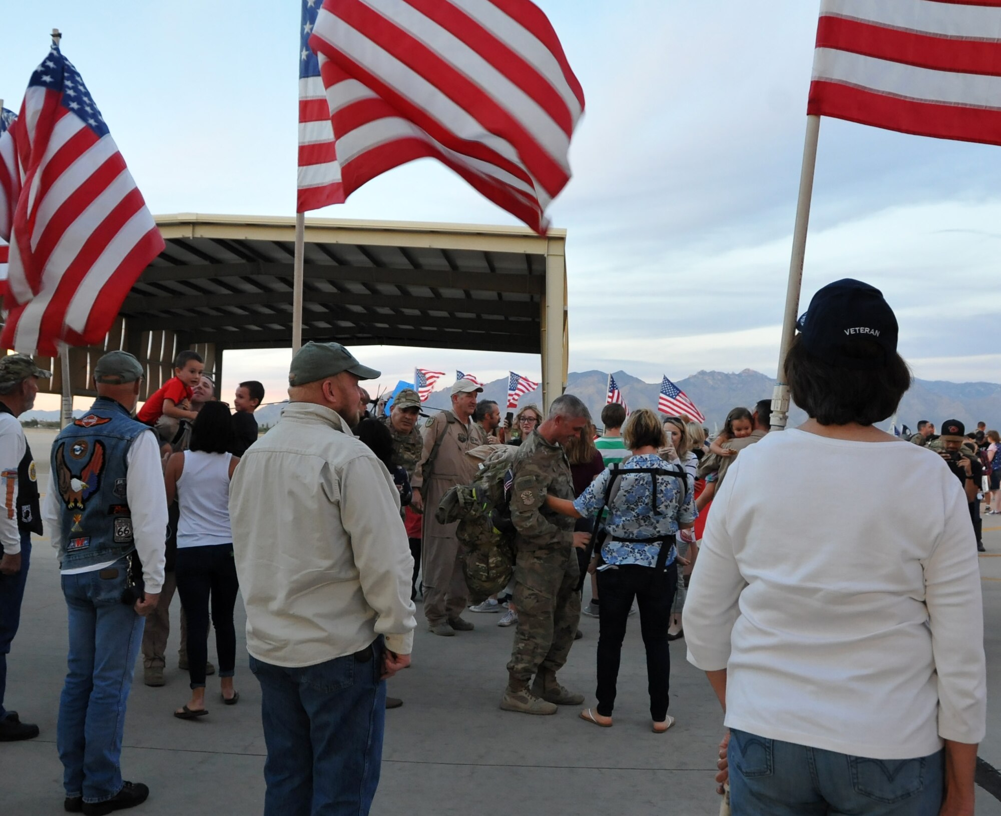 Arizona Patriot Guard Riders stand with American Flags as family and friends welcome home 943rd RQG Airmen.