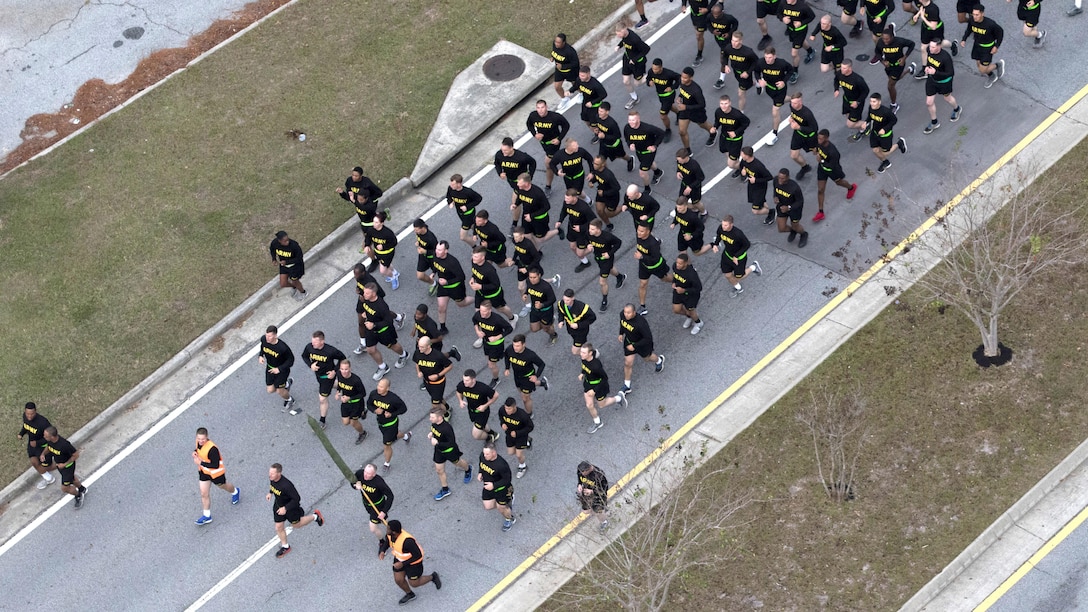 Soldiers, seen from overhead, run in a group on a road.