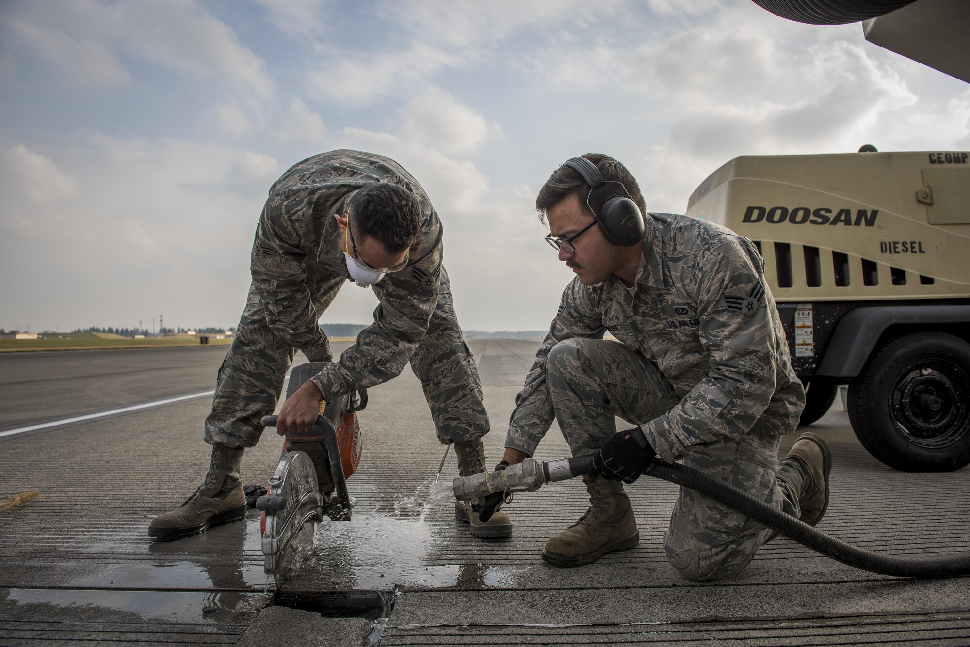 Senior Airman Imran Farooqi, left, and Senior Airman Brendan Kinser, both 374th Civil Engineer Squadron pavements and equipment journeymen, work together to cut a concrete fracture out of the runway, Nov. 15, 2017, at Yokota Air Base, Japan.