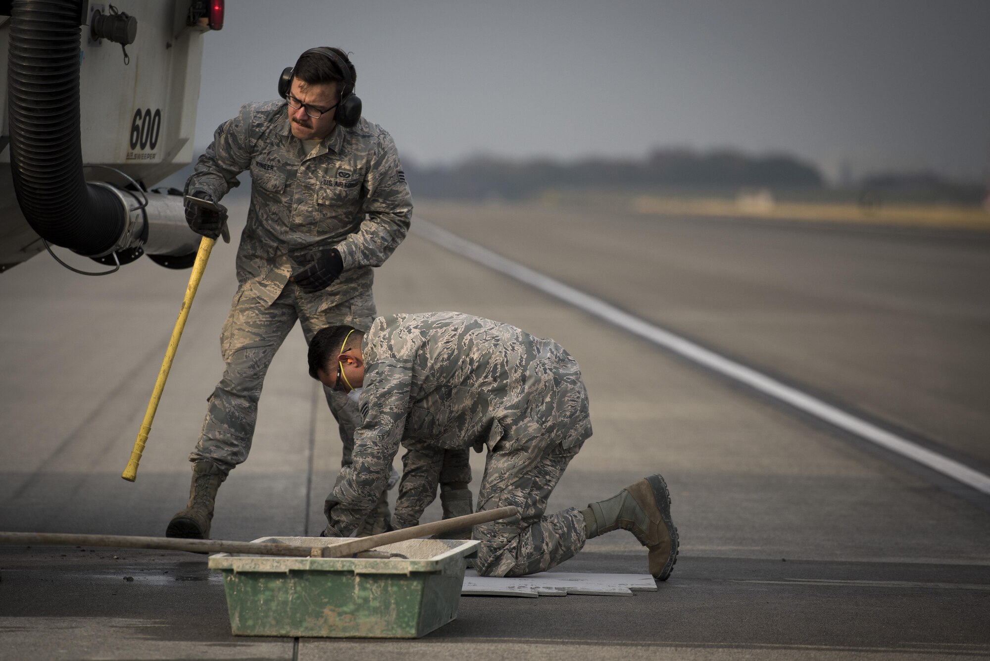 Senior Airman Brendan Kinser, left, and Senior Airman Imran Farooqi, both 374th Civil Engineer Squadron pavements and equipment journeymen, work to repair part of the runway, Nov. 15, 2017, at Yokota Air Base, Japan.