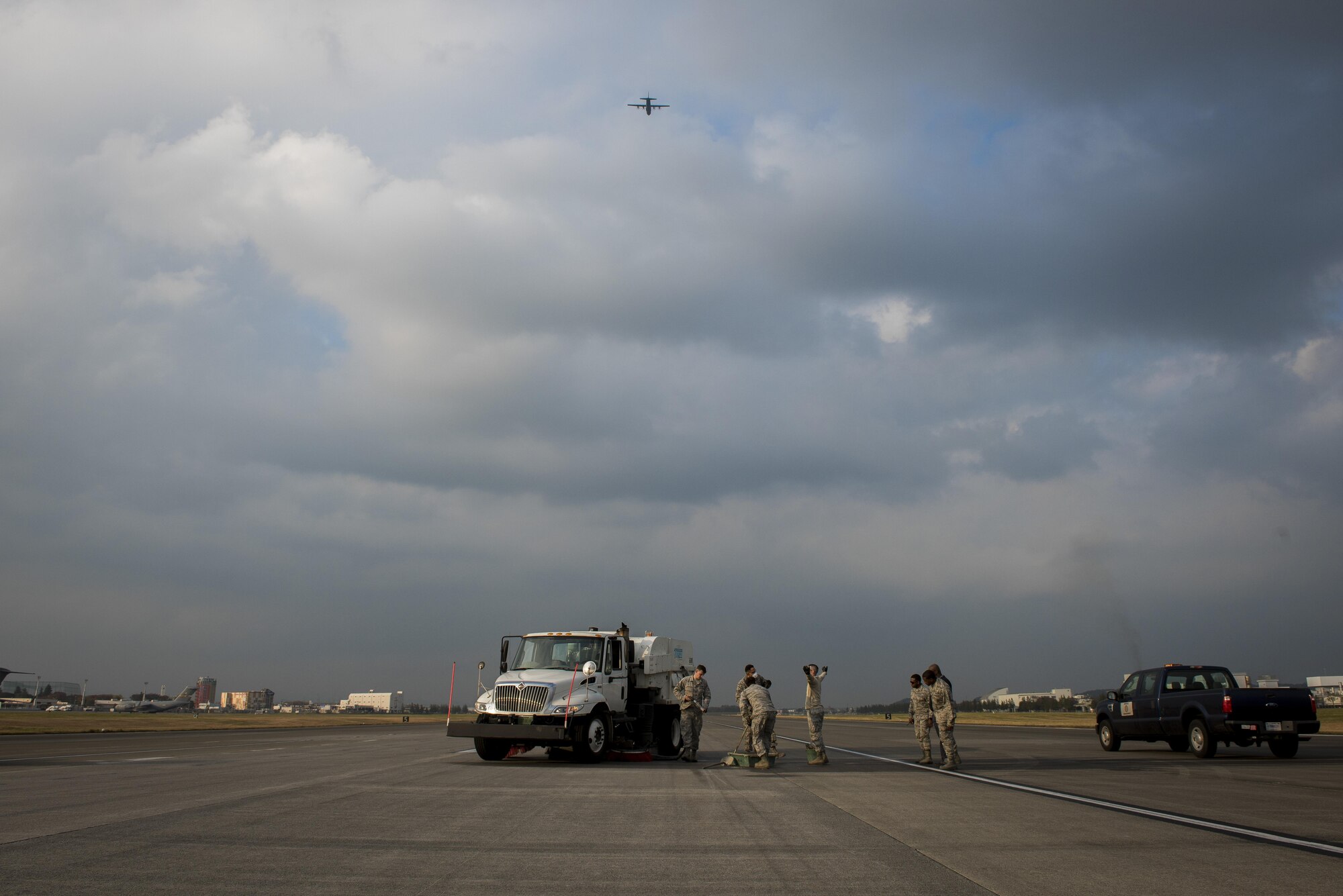 Pavements and equipment journeymen with the 374th Civil Engineer Squadron repair part of the runway as a C-130J Super Hercules passes overhead, Nov. 15, 2017, at Yokota Air Base, Japan.