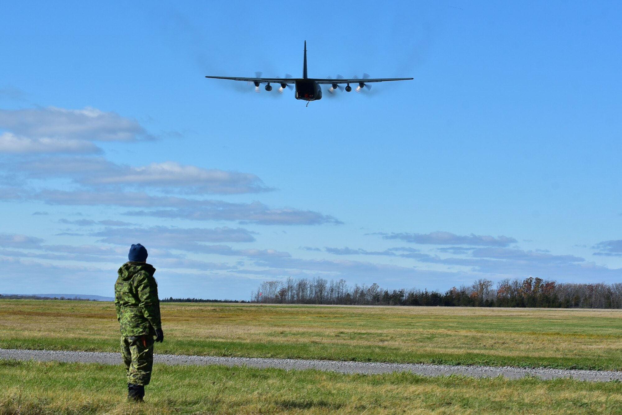Sergeant Steve Peacock watches a Royal Canadian Air Force C-130H do a low-altitude fly by Nov. 6, 2017, at Canadian Forces base Trenton in Ontario, Canada. The 41st Airlift Squadron, 61st Airlfit Squadron and the 19th Airlfit Wing were invited by the Royal Canadian Air Force to perform exercises in adverse weather conditions. (U.S. Air Force photo by Airman Rhett Isbell)