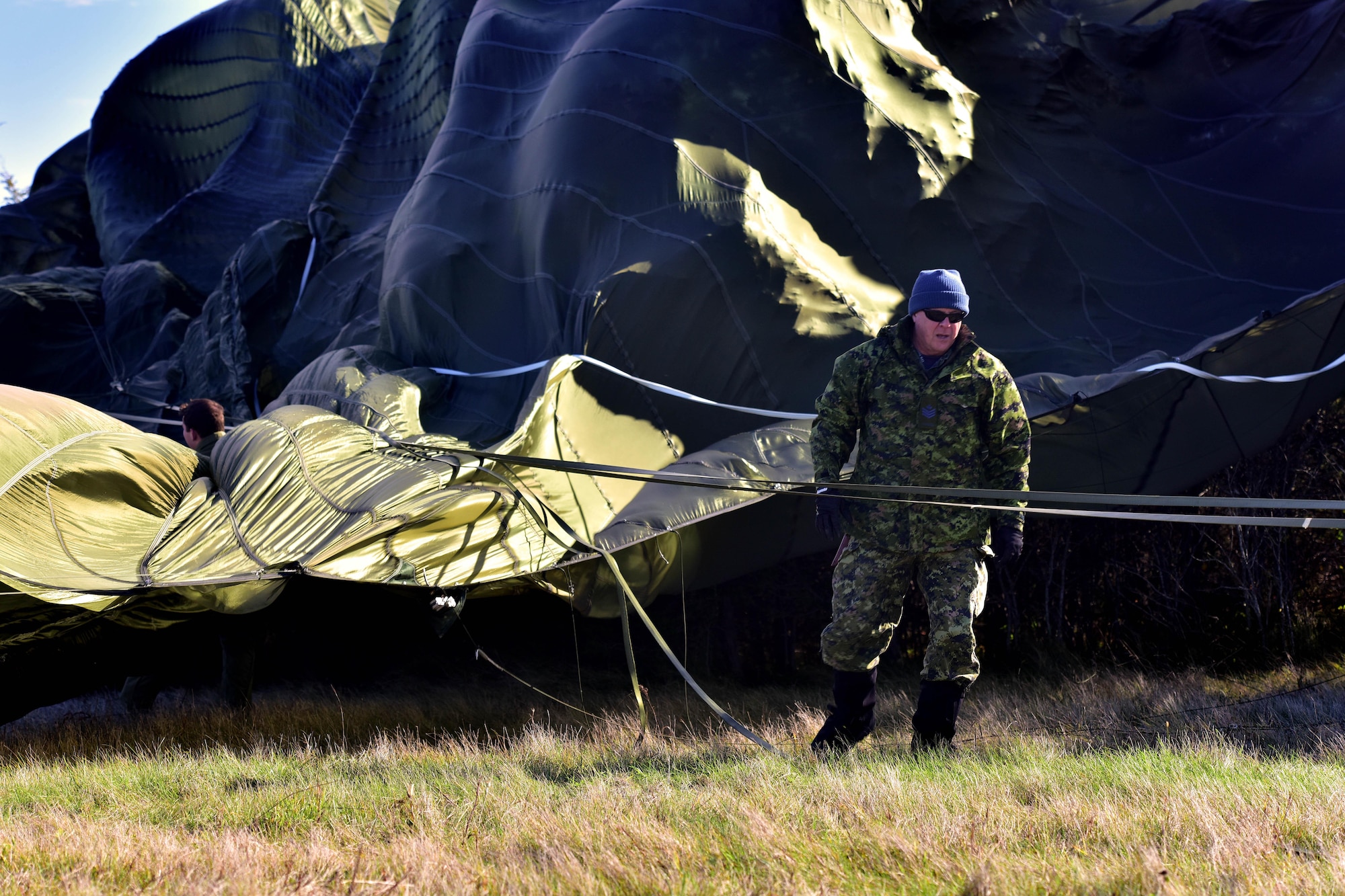 Royal Canadian Air Force Sergeant Steve Peacock, 8 Wing Trenton Combat Aerial delivery support section, works to free a large parachute from trees after it had missed it's target at Canadian Forces base Trenton in Ontario, Canada, Nov. 6, 2017.  The large Container Delivery System had just missed the target and the high winds dragged it into the nearby woods.  (U.S. Air Force photo by SSgt Jeremy McGuffin)