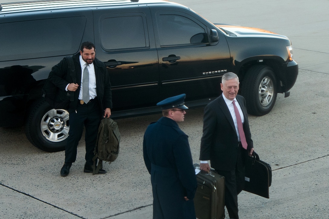 Defense Secretary Jim Mattis walks away from a vehicle carrying bags.