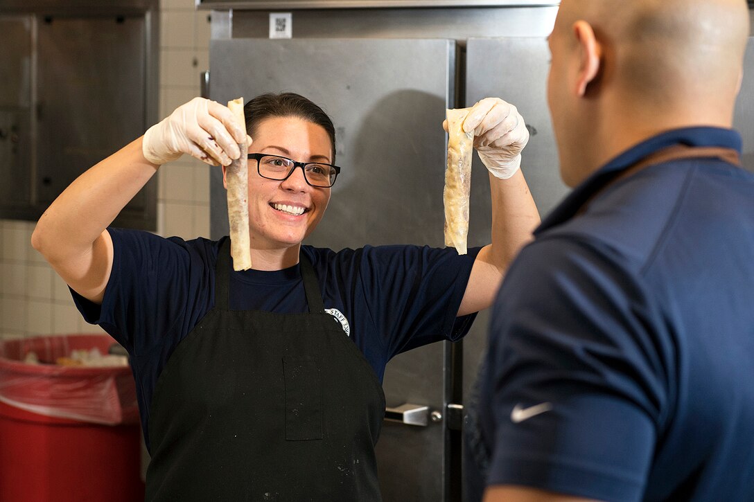Airman shows off her cooking done during the USO Salute to Military Chefs dinner.