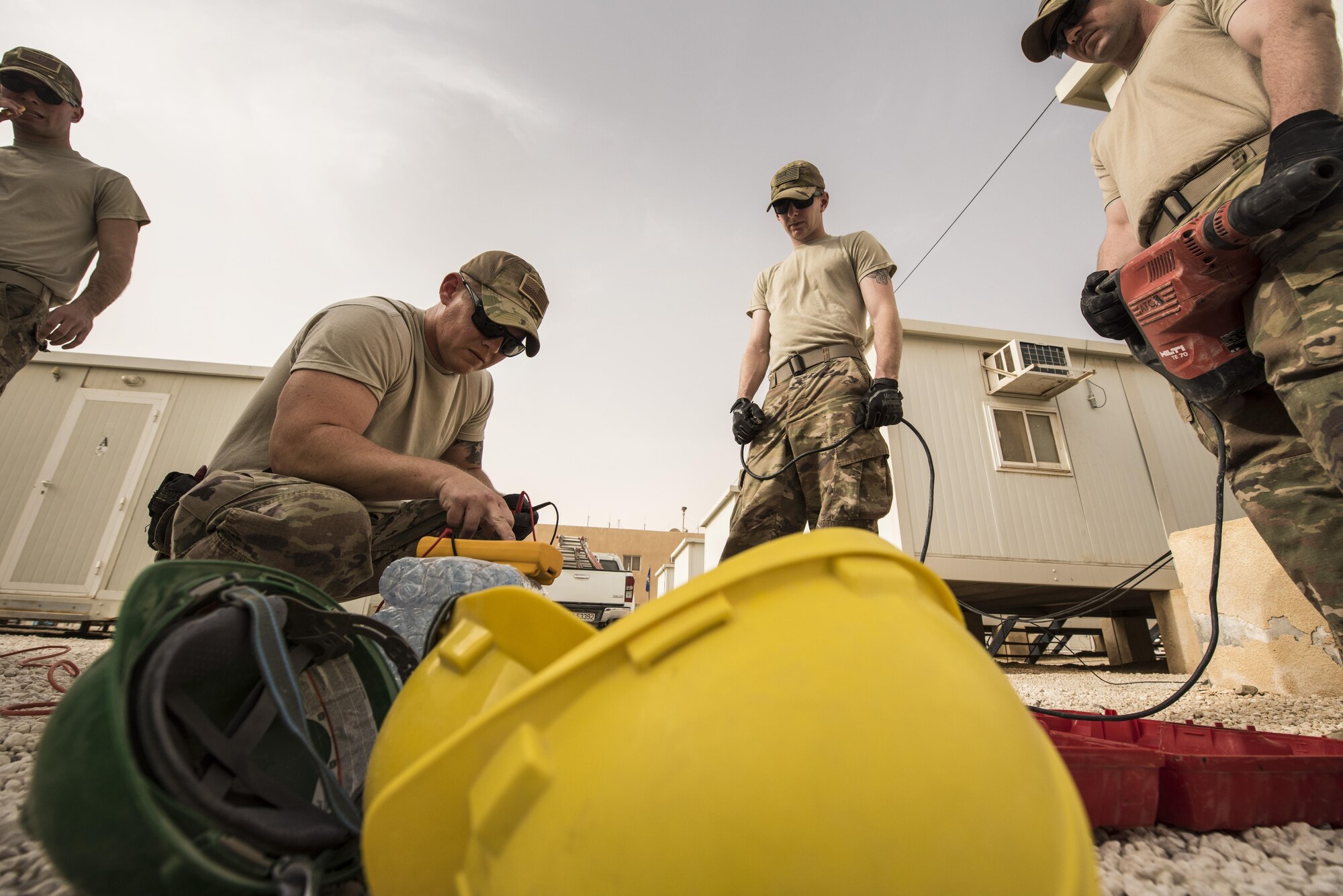 Airmen from the 332nd Expeditionary Communications Squadron set up power for their tools before starting a base-wide wireless internet improvement project Nov. 13, 2017 in Southwest Asia. The project required that the team run copper wire both underground and across rooftops to establish reliable connectivity in living and recreation areas. (U.S. Air Force by Senior Airman Joshua Kleinholz)