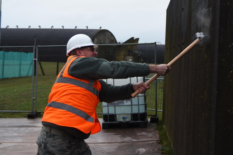 Col. Evan Pettus, 48th Fighter Wing commander, swings a sledgehammer during a demolition ceremony Nov. 8 at Royal Air Force Lakenheath, England. The ceremony marked the first physical step in developing the infrastructure needed for the wing’s future F-35A Lightning II squadrons. (U.S. Air Force photo/Airman 1st Class Christopher S. Sparks)