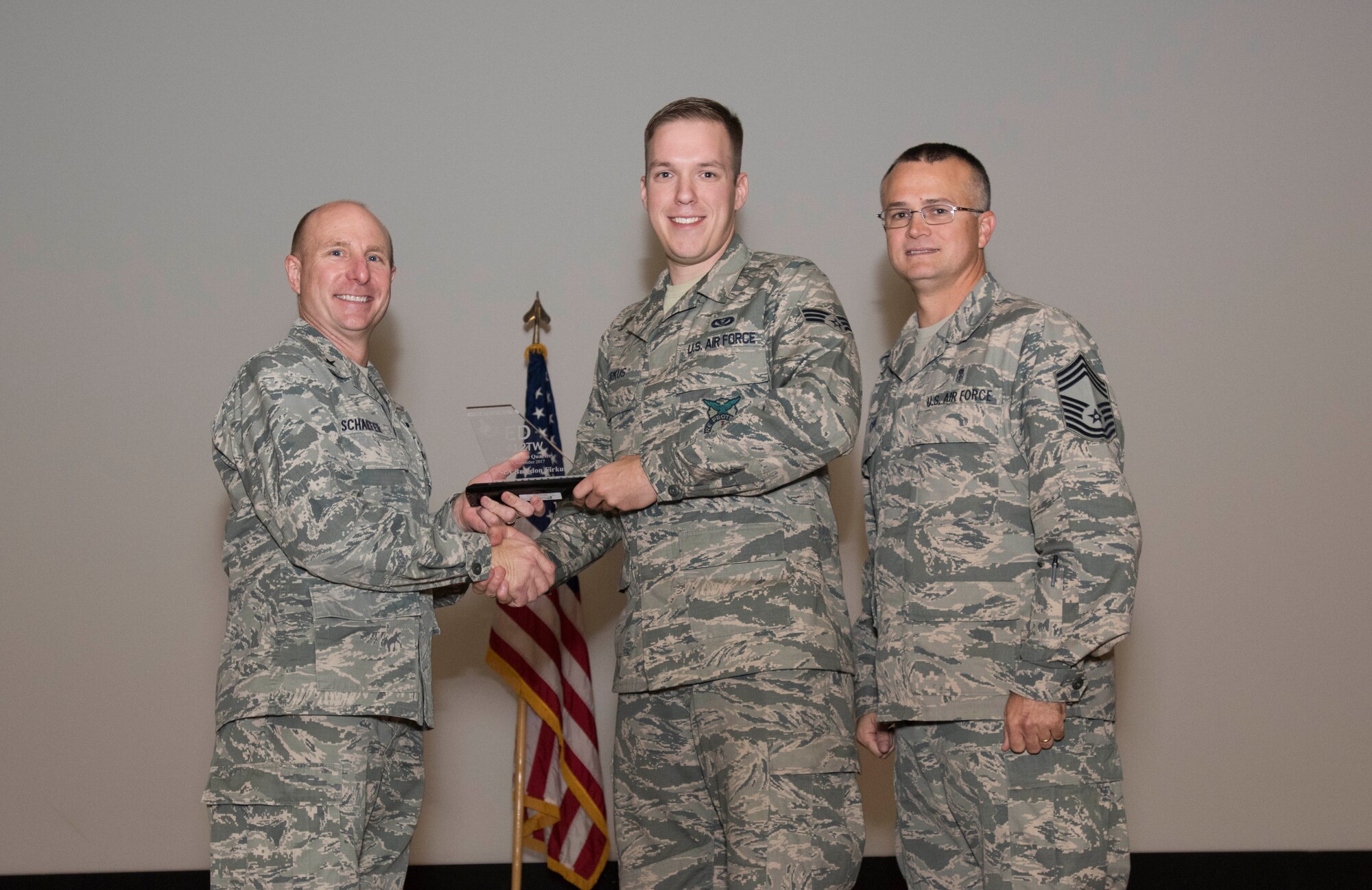 From left: Brig. Gen. Carl Schaefer, 412th Test Wing commander, presents Senior Airman Braedon Firkus, 812th Civil Engineer Squadron Fire Protection, with the 412th TW Airman of the Quarter award, along with Chief Master Sgt. Donald Cook, 412th Medical Group chief. The wing held its third quarter awards ceremony at the base theater Nov. 14. (U.S. Air Force photo by Brad White)
