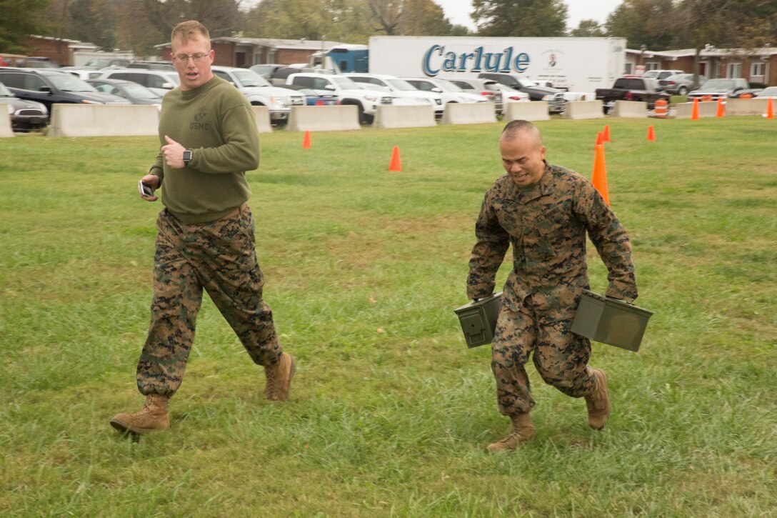 Gunnery Sgt. Jeffrey Sabins, training chief, S3, Headquarters and Service Battalion, U.S. Marine Corps Forces Command follows Sgt. Terry Chung, data network administrator, G6, U.S. Marine Corps Forces Command, as he carries two 30-pound ammo cans as part of the maneuver under fire event of the combat fitness test at the Headquarters and Service Battalion building, at Camp Allen, Norfolk, Va., Nov. 15. Marines were required to carry the ammo cans twice during the event, running more than 150 yards in total. (Official Marine Corps photo by Chris Jones/Released)