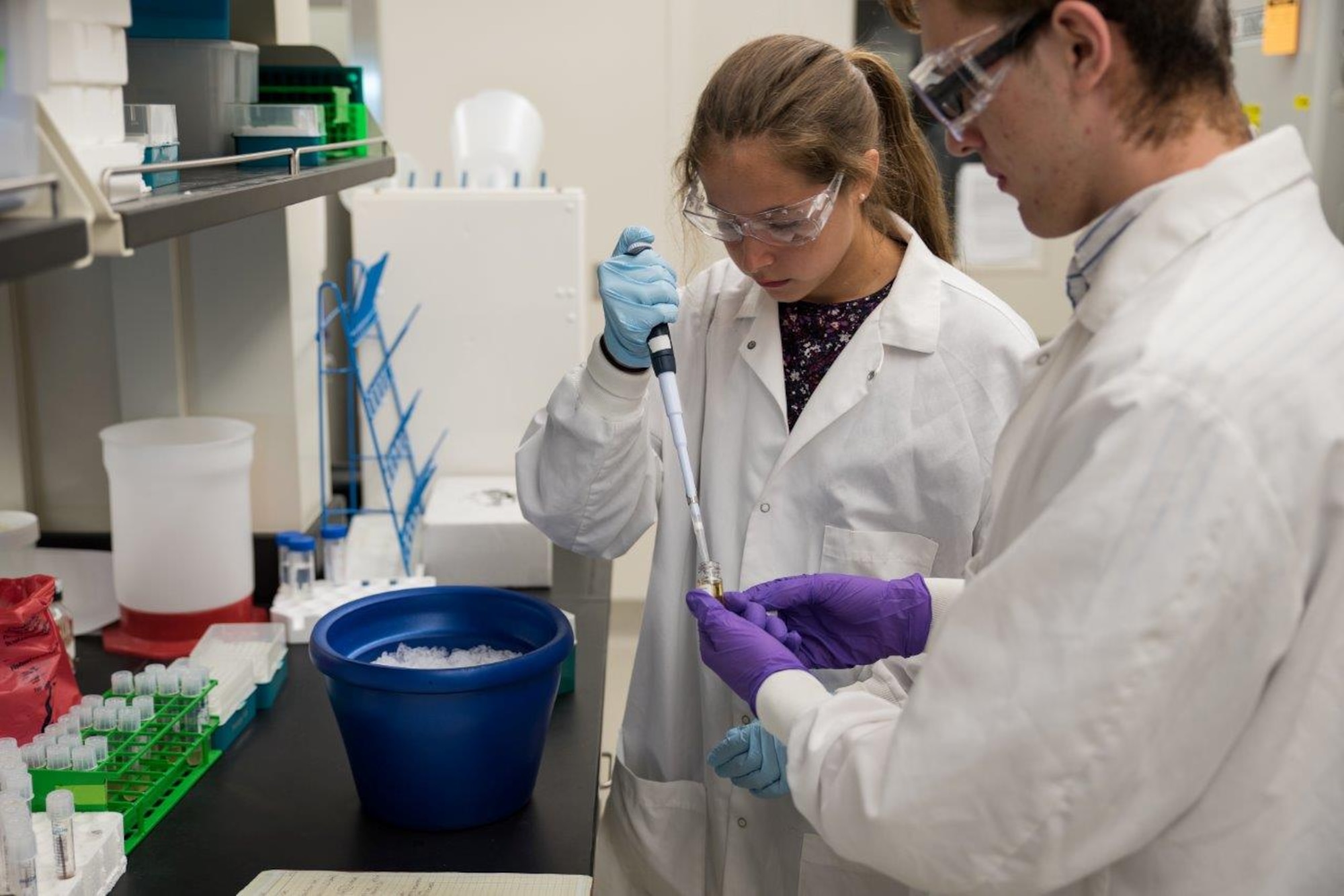 Tina Davis and Peter Menart, members of the Air Force Research Laboratory-Carroll High School iGEM team, use a pipette as they work on their synthetic biology project in a laboratory in the 711th Human Performance Wing prior to the iGEM competition in Boston. (U.S. Air Force photo/Richard Eldridge)