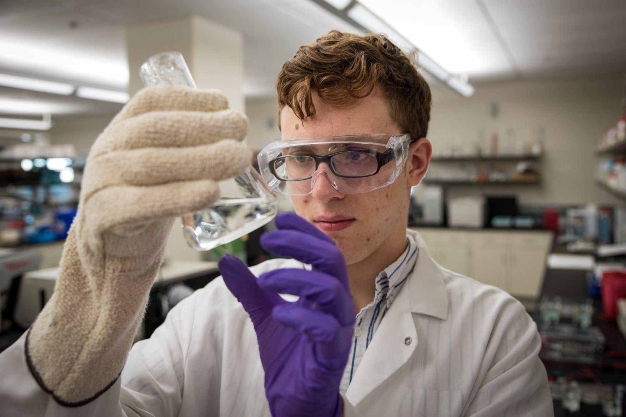 Peter Menart, member of the Air Force Research Laboratory-Carroll High School iGEM team, examines liquid in a beaker during the laboratory phase of the team’s project prior to the iGEM competition in Boston.  (U.S. Air Force photo/Richard Eldridge)