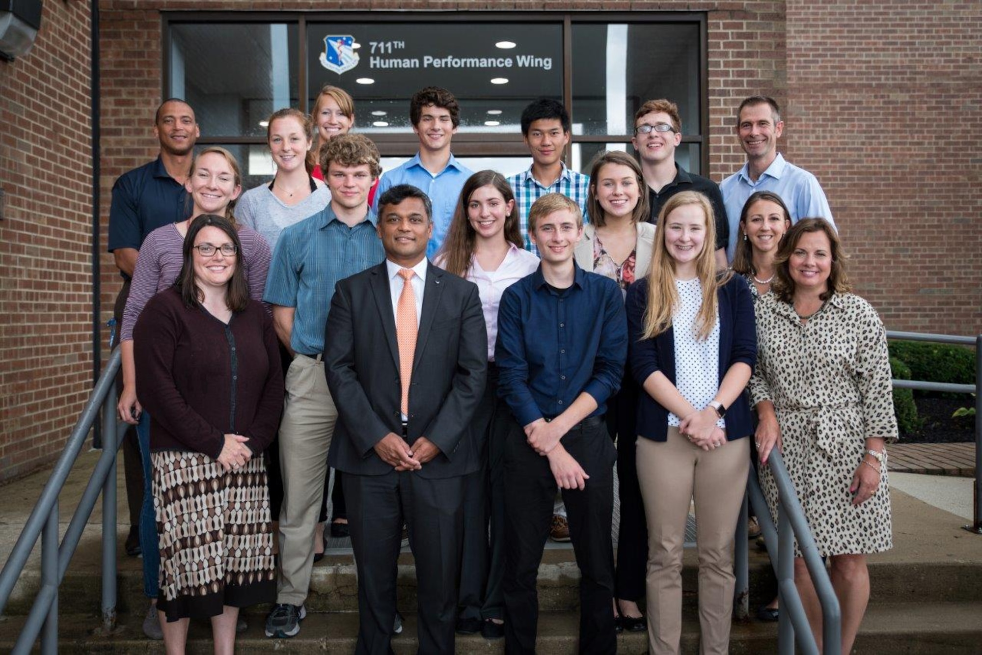 Members of the Air Force Research Laboratory-Carroll High School iGEM team stand with their CHS teachers and AFRL mentors in front of the 711th Human Performance Wing headquarters building following a presentation given to the 711HPW Chief Scientist Dr. Rajesh Naik (front, second from left).  (U.S. Air Force photo/Richard Eldridge)