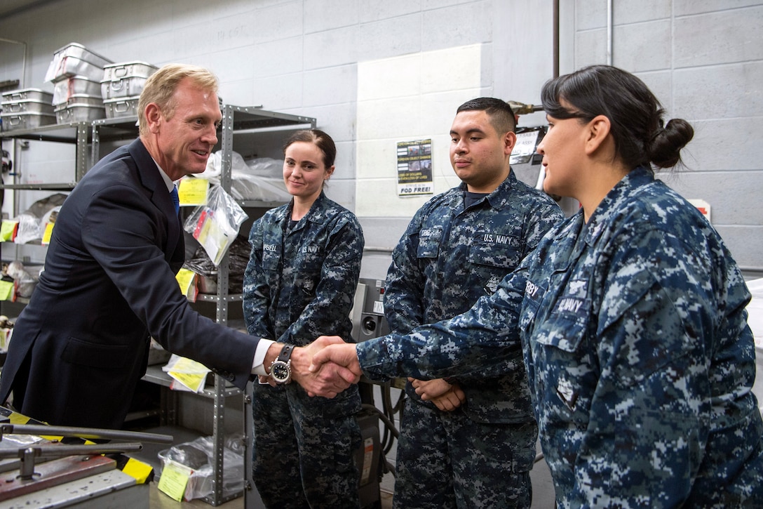 Deputy Defense Secretary Pat Shanahan shakes hands with a sailor as two other sailors look on.