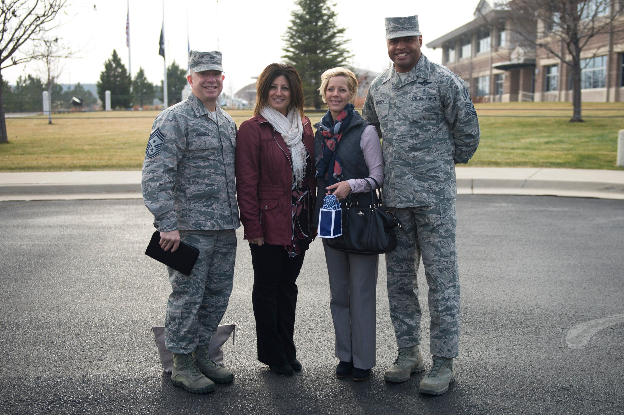 Chief Master Sgt. Brendan I. Criswell, Command Chief Master Sergeant, Air Force Space Command, his wife, Christine, Chief Master Sgt. Rod Lindsey, 460th Space Wing command chief, and his wife, Stacy, pose for a photo in front of the 460th Space Wing Headquarters Nov. 9, 2017, on Buckley Air Force Base, Colo.