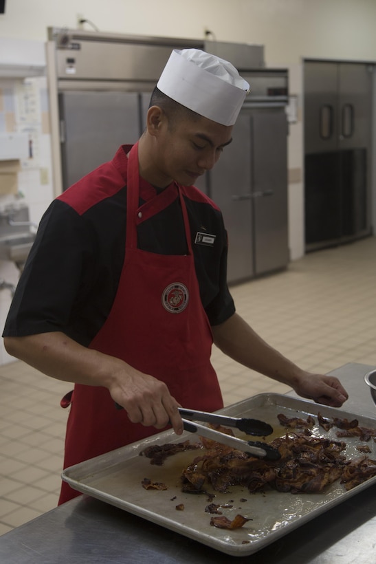 CAMP FOSTER, OKINAWA, Japan – Lance Cpl. Zoren Legaspi prepares bacon for the salad bar Nov. 11 in Mess Hall 488 aboard Camp Foster, Okinawa, Japan.