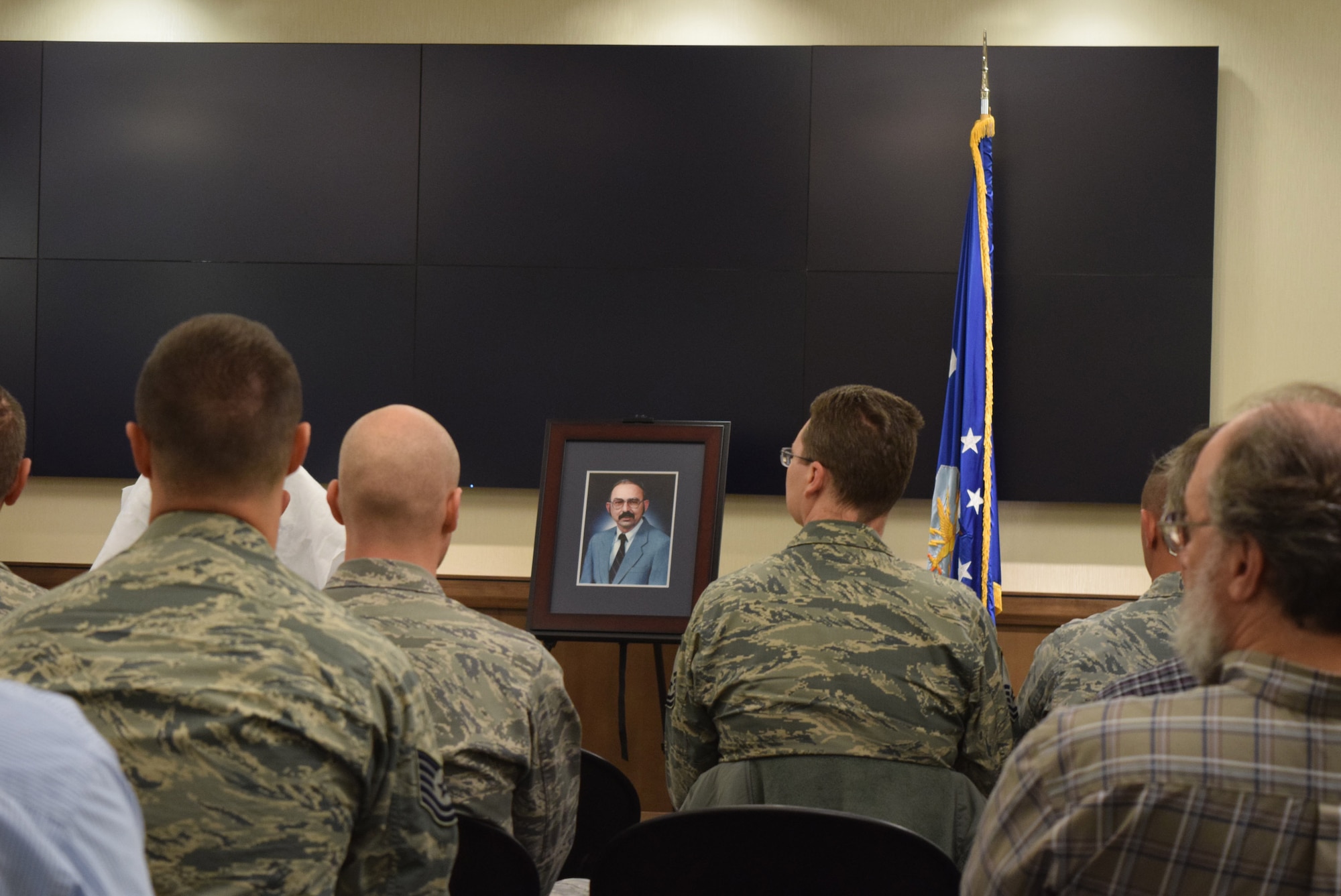 Members of the Harkins Laboratory Complex at Cheyenne Mountain Air Force Station, Colo., listen to remarks from Col. Steven M. Gorski, commander of the Air Force Technical Applications Center, during the dedication ceremony that named the lab after Michael Harkins, a former AFTAC senior scientist.  Harkins’ official portrait is seen in the center of photo.  (U.S. Air Force photo by Susan A. Romano)