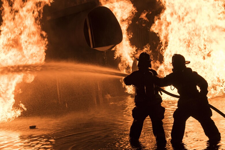 Firefighters work to put out a blaze during nighttime live-fire training, Nov. 9, 2017, at Moody Air Force Base, Ga. In addition to combatting fires outside the prop aircraft, firefighters had to enter and combat the fires inside. (U.S. Air Force photo by Senior Airman Janiqua P. Robinson)