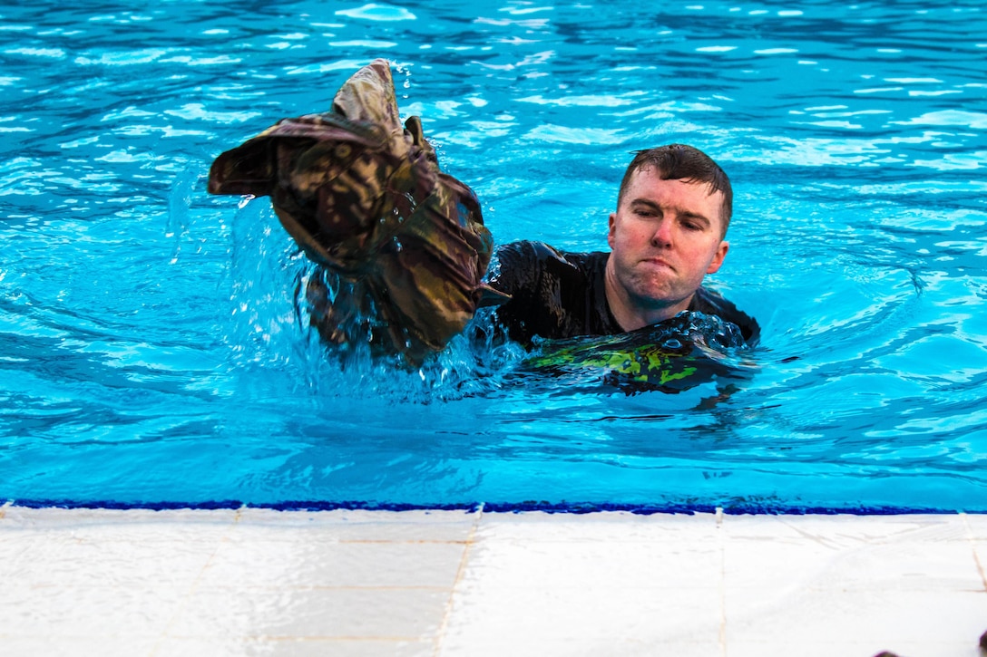 A soldier throws part of a uniform out of the pool.