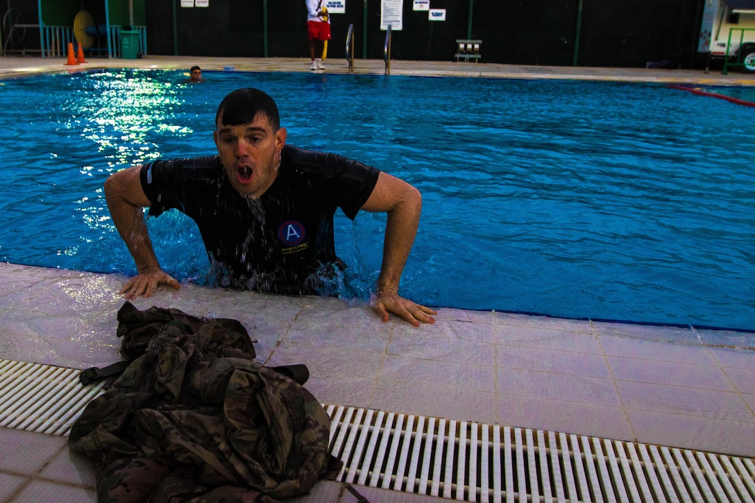 A soldier pulls himself out of a pool.