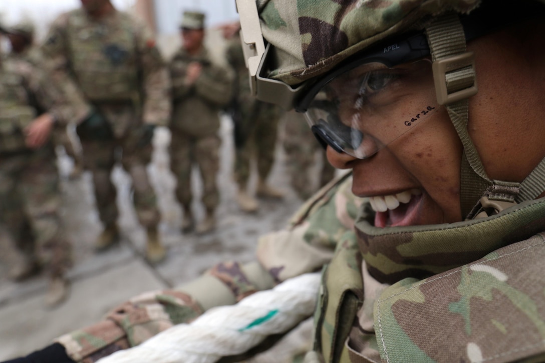 A soldiers smiles as she takes part in a tug of war event.