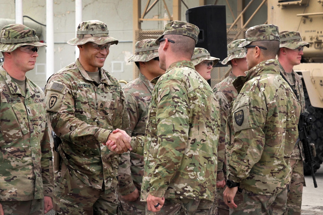 Officers shake hands with soldiers during a coin presentation in Afghanistan.