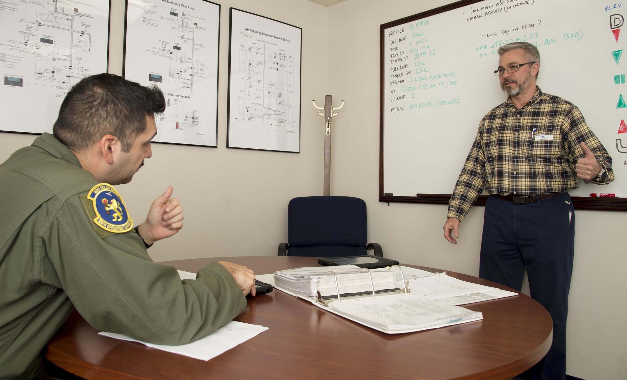 U.S. Air Force Tech. Sgt. Augie Marshall, wing scheduler assigned to the 100th Operations Support Squadron (OSS), talks to John Mercer, a Boom Operator Weapon System Trainer (BOWST)  Instructor assigned to the 6th OSS, about BOWST procedures, Nov. 8, 2017, at MacDill Air Force Base, Fla. The BOWST creates a platform to instruct Airmen assigned to the MacDill BOWST to Airmen from around the world. (U.S. Air Force photo by Senior Airman Mariette Adams)