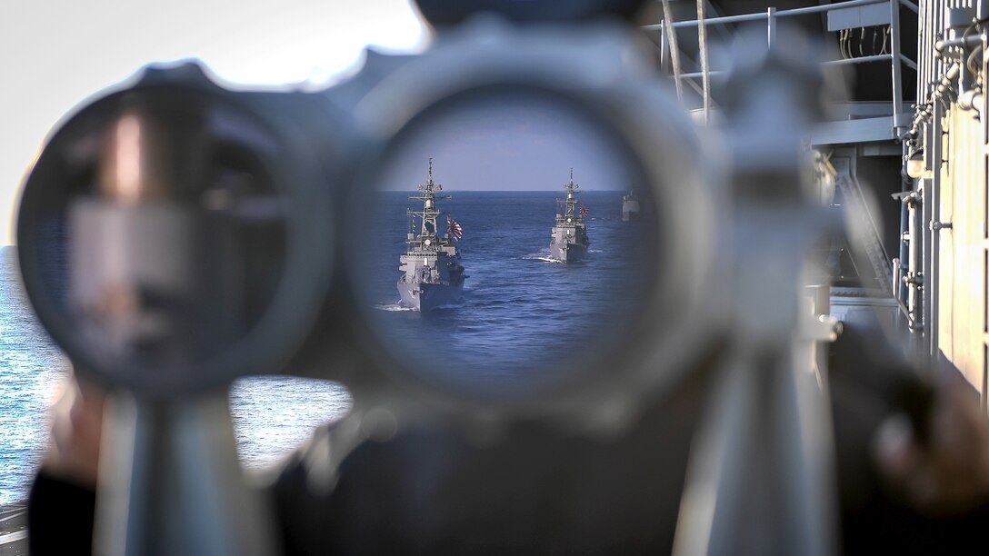 Two ships in the ocean are visible in a binocular lens aboard a ship.