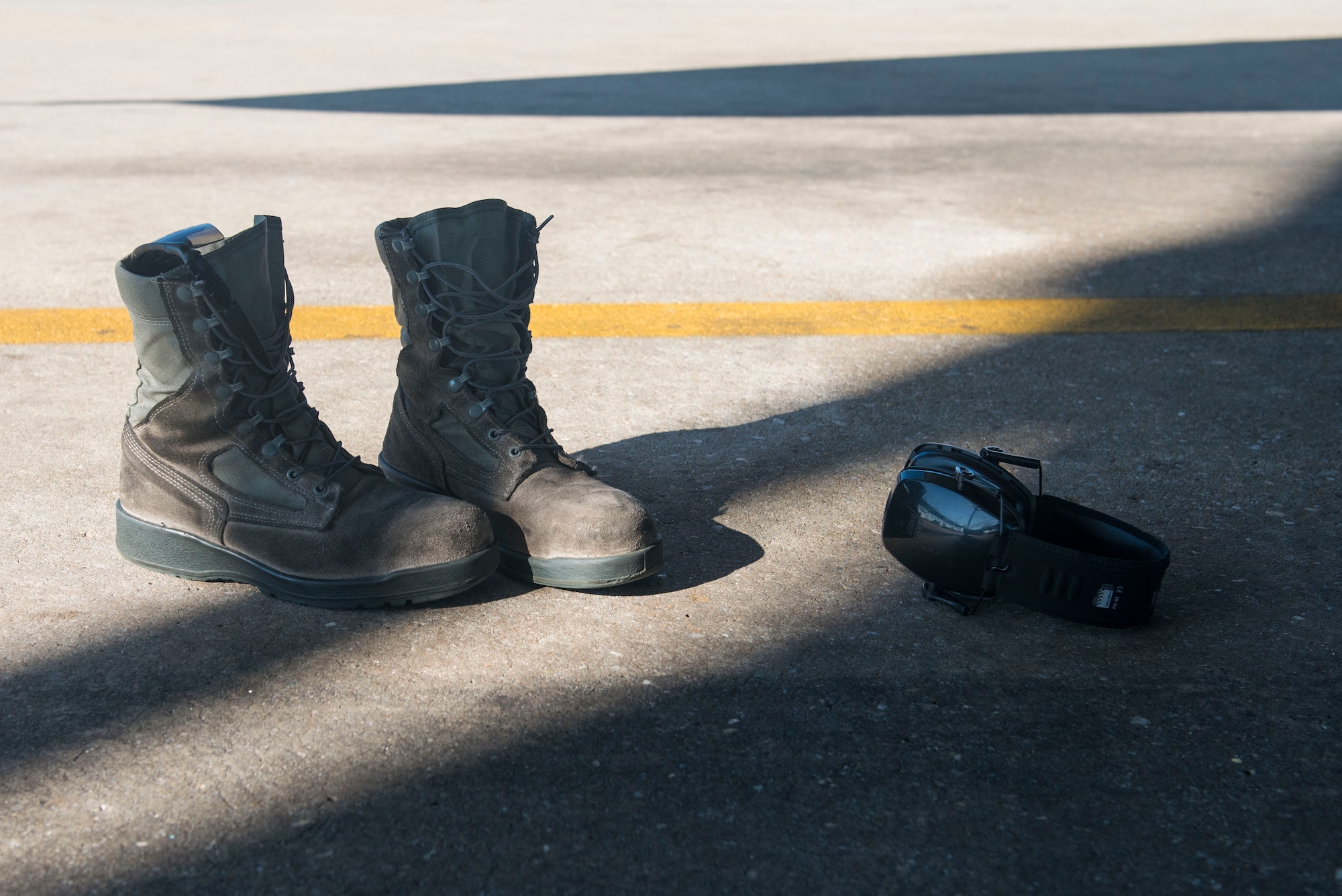 A pair of boots and hearing-protective earphones lie on the ground after being set aside by an Airman prior to climbing into the intake of an F-16CM Fighting Falcon at Shaw Air Force Base, South Carolina, Nov. 16, 2017.
