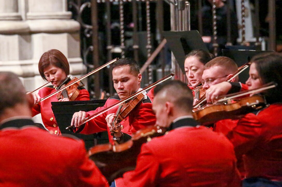 Marines in red uniforms play violins inside a cathedral.