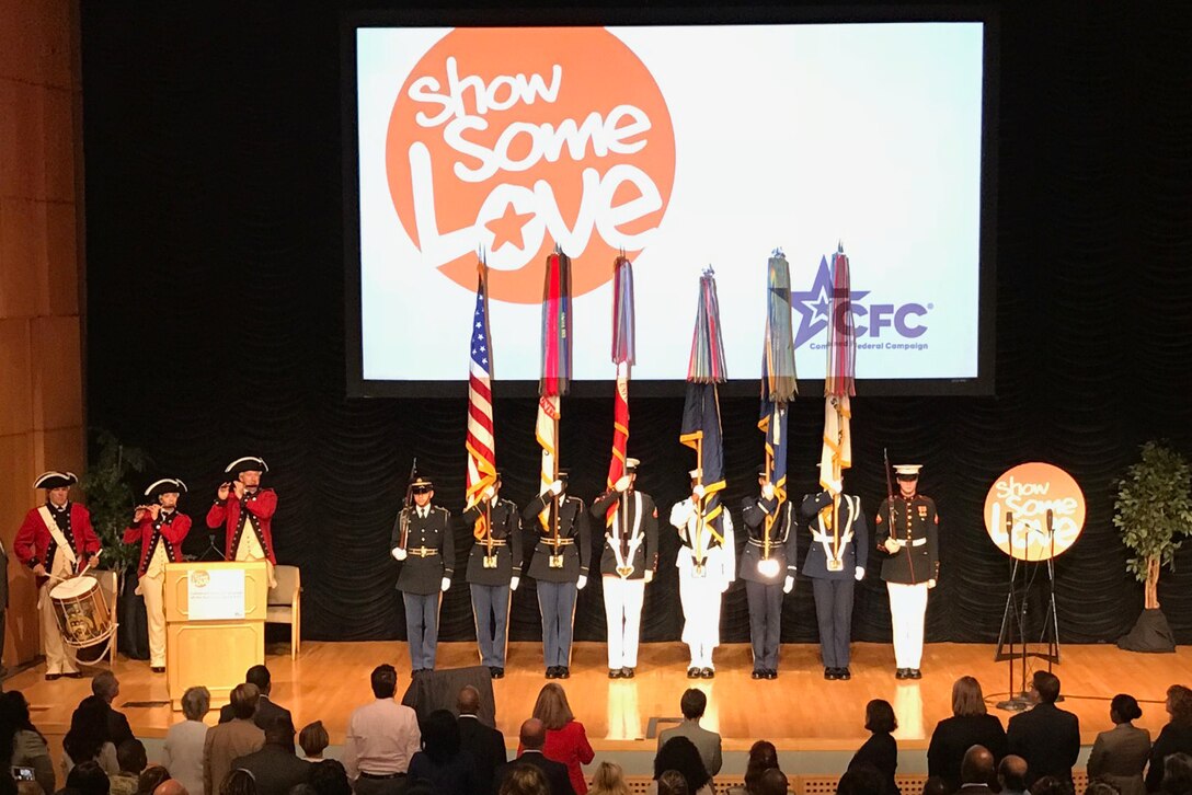 Service Members display flags on stage.