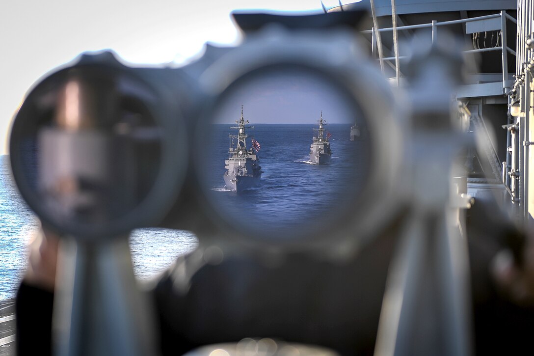 Two ships in the ocean are visible in a binocular lens aboard a ship.