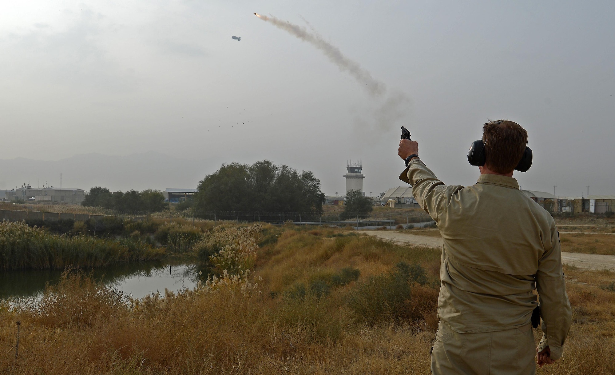 James Capps, 455th Air Expeditionary Wing U.S. Department of Agriculture (APHIS) and BASH forward operating base biologist, shoots off a pyrotechnic to harass wildlife off of Coyote Creek, Nov. 21, 2017 at Bagram Airfield, Afghanistan.