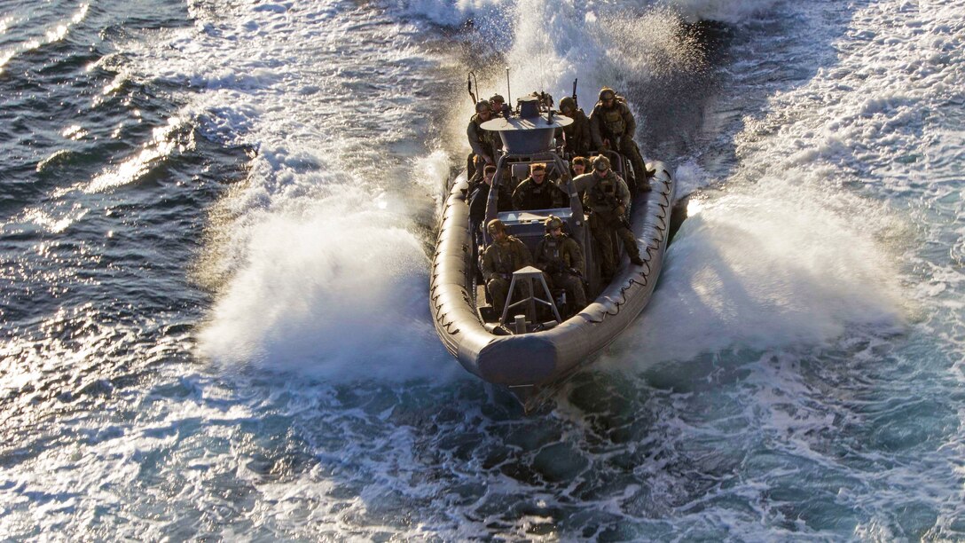 A craft carrying Marines make waves in water.