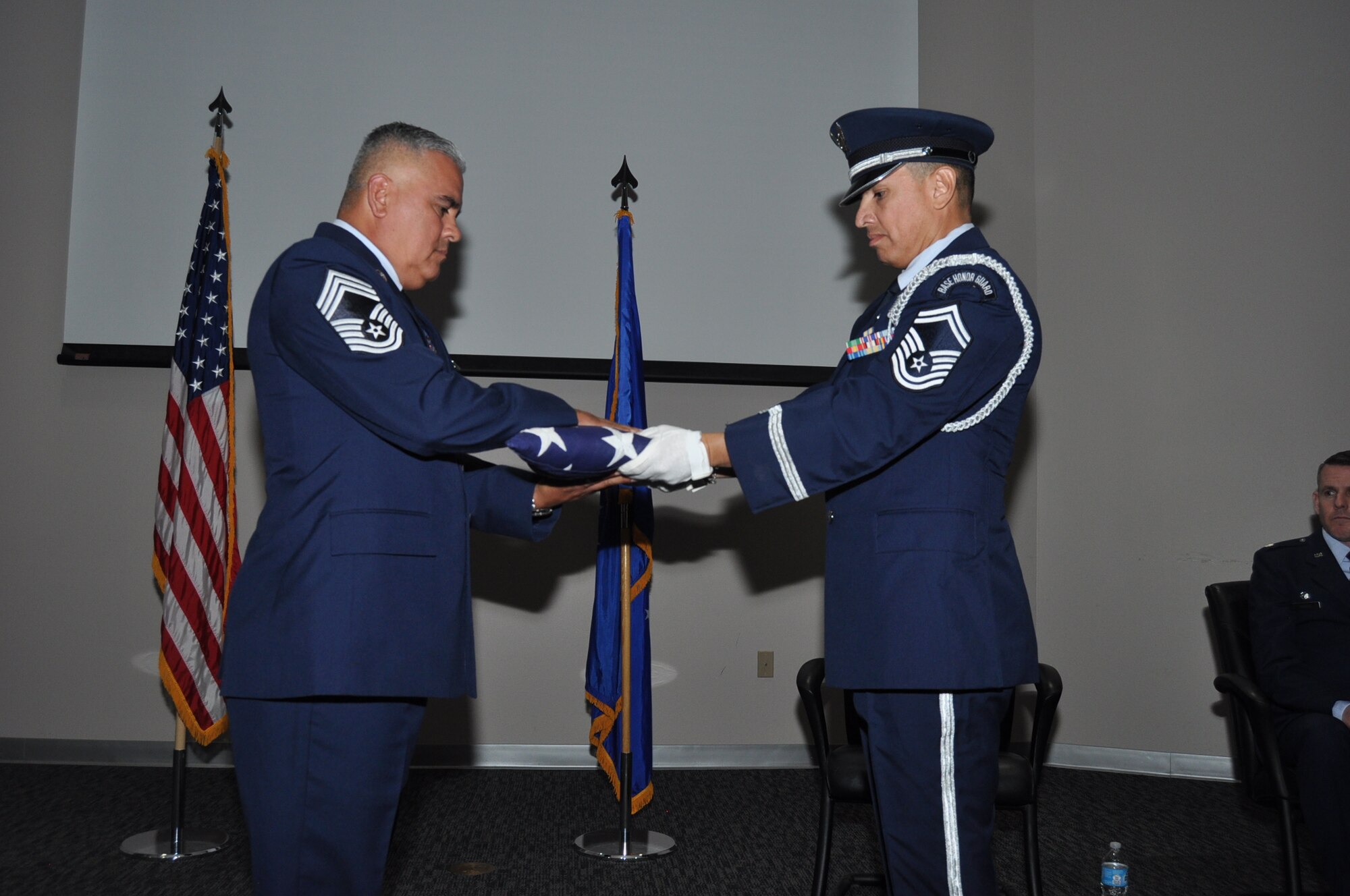 (Left) Chief Master Sgt. Daniel Martinez Jr., previous 26th Aerial Port Squadron operations superintendent, receives a ceremonial flag during his retirement ceremony here Nov. 18, 2017. Chief Martinez retires after 32 years of service in the Air Force Reserves, all spent with the 433rd Airlift Wing. He deployed seven times throughout his career; twice to Columbia, twice to Germany, and once to Spain, Iraq and Afghanistan.