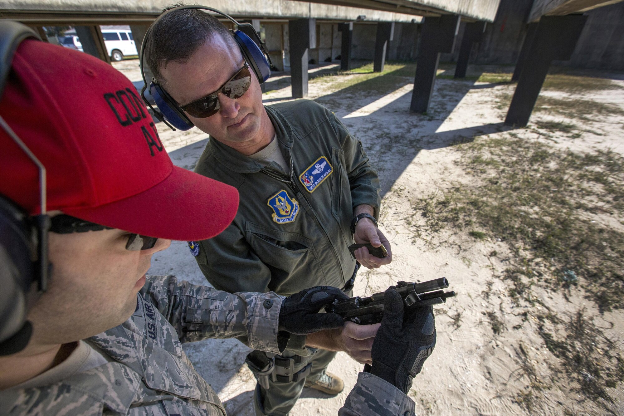 U.S. Air Force Staff Sgt. Michael Chiarella, left, Combat Arms Training and Maintenance Instructor, 514th Security Forces Squadron, assists Senior Master Sgt. Shawn R. Reynolds, C-17 Globemaster III Loadmaster, 732nd Airlift Squadron, 514th Air Mobility Wing, in removing a 9 mm round from an M9 pistol