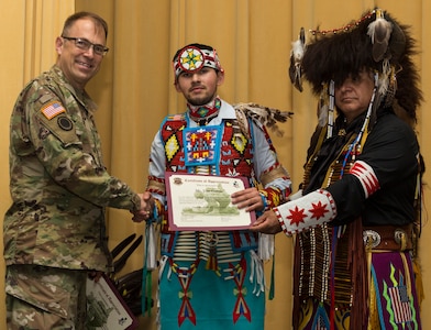 Jose Garcia II (center), a member of the American Indians in Texas Dance Theater group, receives a certificate of appreciation from Maj. Gen. Brian Lein, U.S. Army Medical Department Center and School commanding general (left), during the National American Indian Heritage Month Observance Nov. 16 at AMEDDC&S, located at Joint Base San Antonio-Fort Sam Houston. Standing to the right of Garcia is Isaac Cardenas, also a member of the American Indians in Texas Dance Theater group.