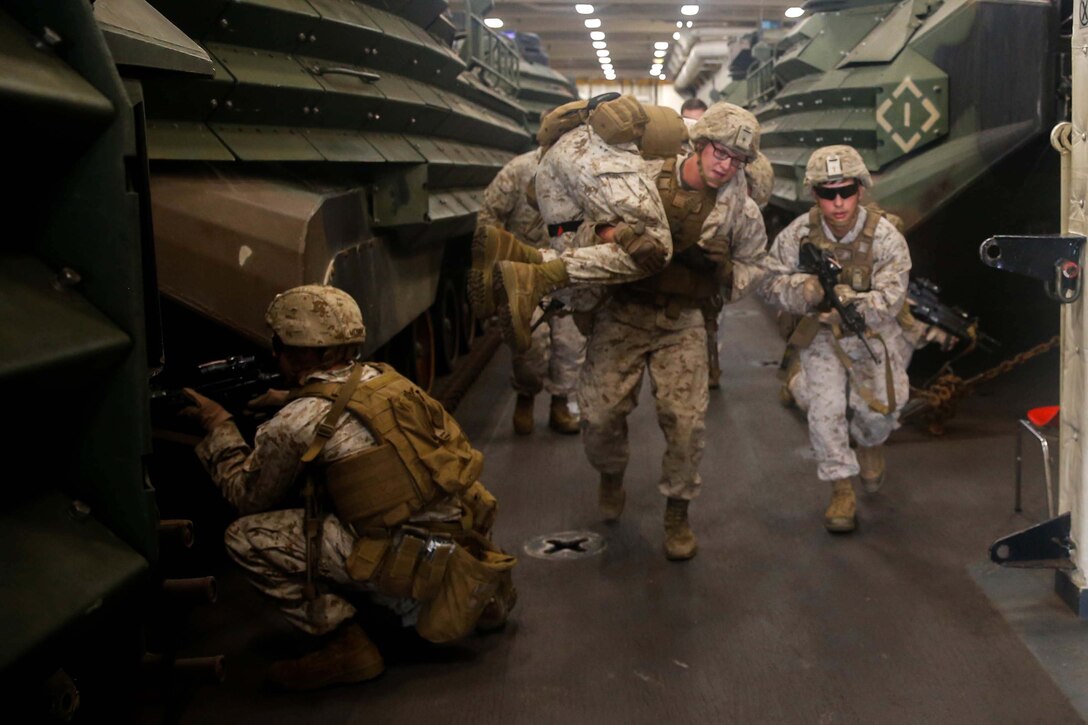 A Marine carries another Marine down a hallway.