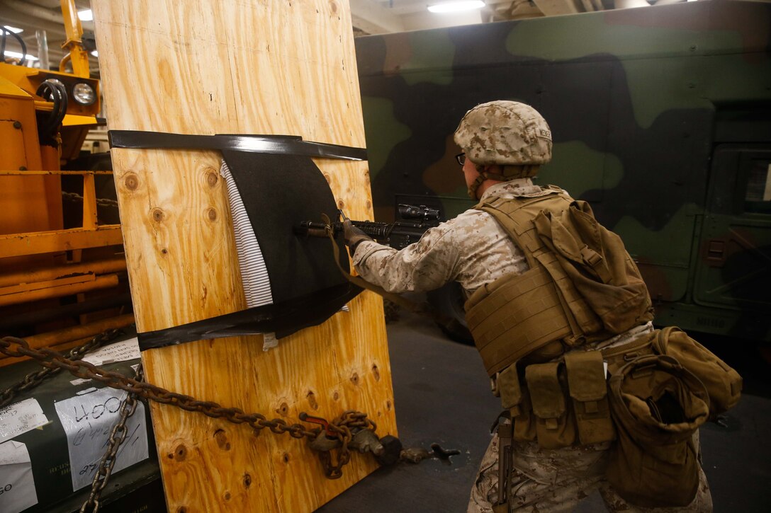 A marine pushes a blade at the end of a firearm into a pad.